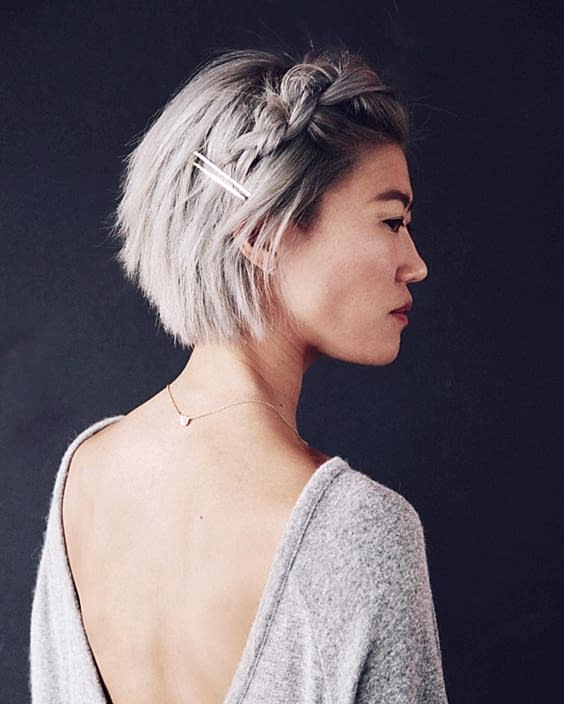 side profile of woman with grey chin-length bob with large chunky braid in front, secured with two long, thin, metallic clips