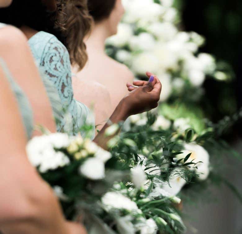 Viewpoint down a line of bridemaids, focus on one of their hands 