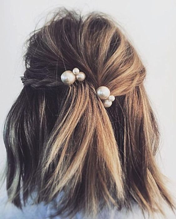 Woman's hair from behind, half up with messy loose braids and two large pearl combs