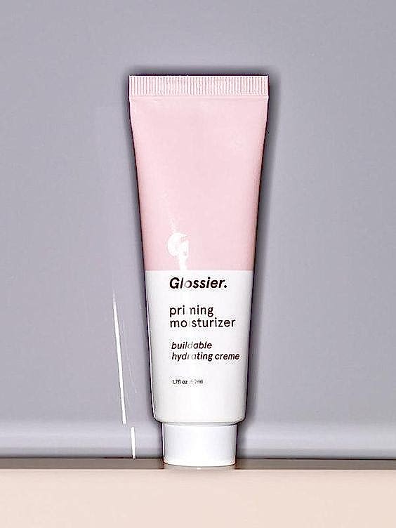 Pink and white tube of Glossier priming moisturizer on gray background