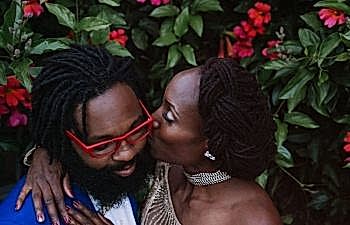 A woman embraces her husband and kisses his cheek