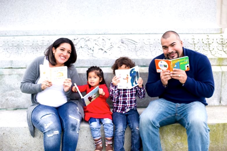 family of four reads board books on a marble step