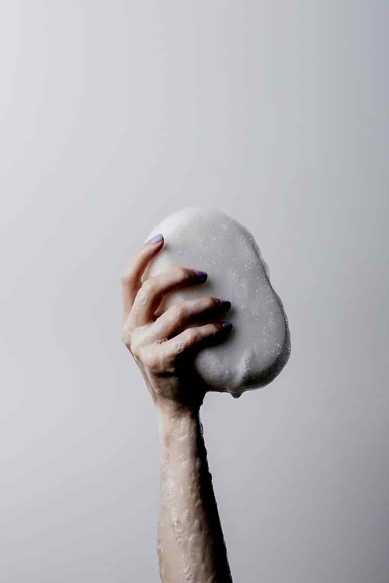 arm holding up bar of soap with lather on arm