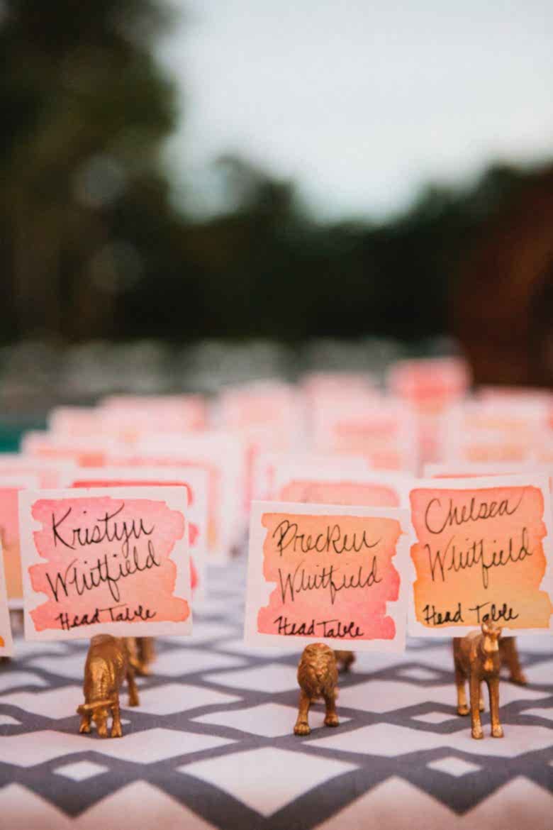 Ombre watercolor place cards in gold plastic animal holders.