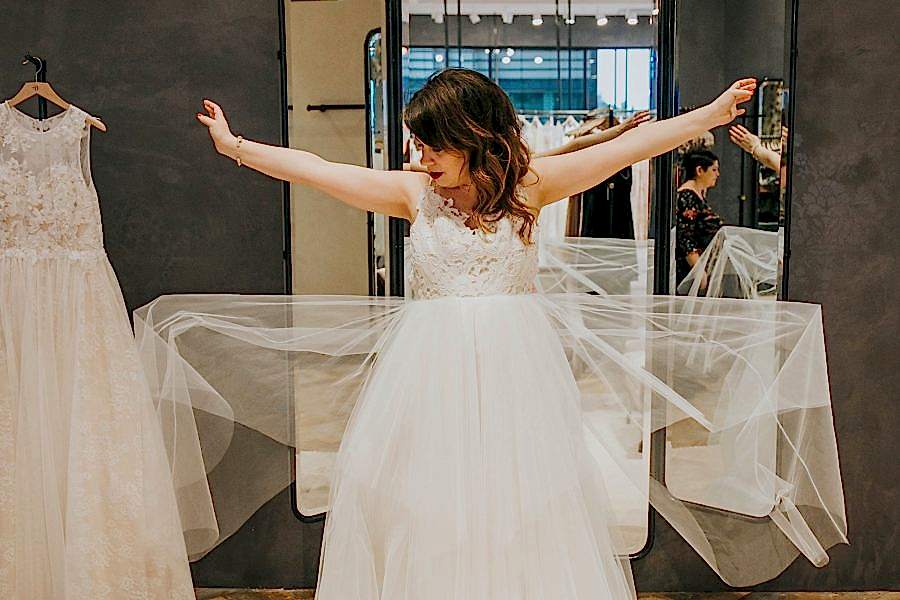 Meg in a wedding gown in front of the store's mirror