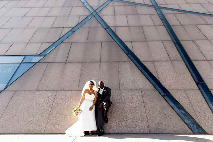 A wedding couple lean against a wall