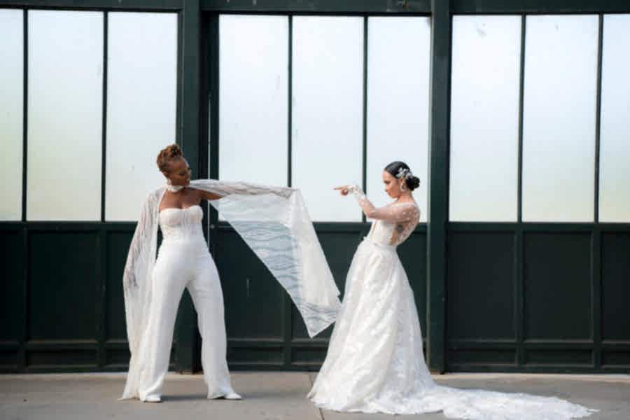 A wedding couple posing in front of a wall