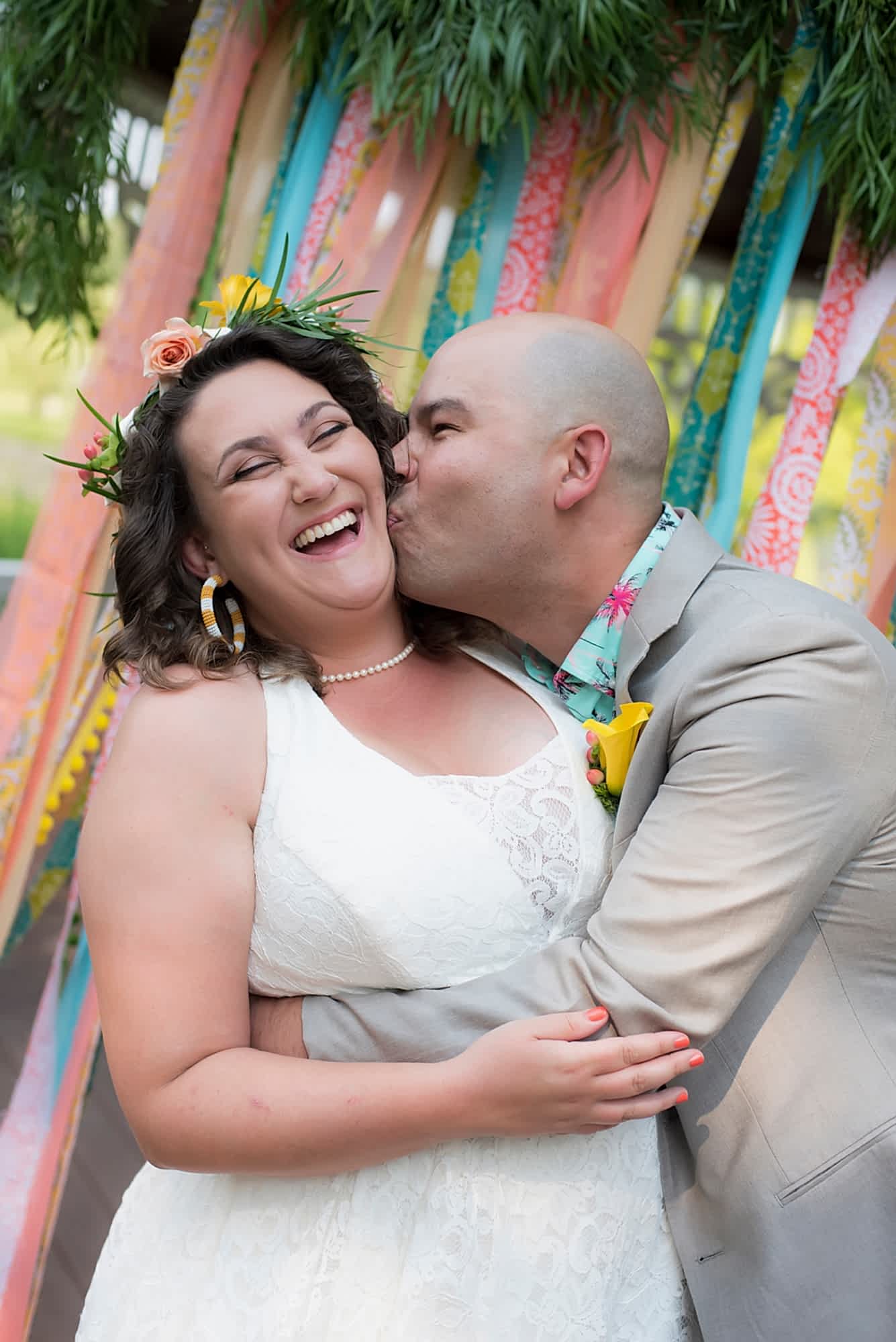 A man kisses a woman's cheek on their wedding day.