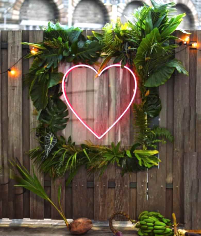 neon-style pink heart inside tropical leaf frame