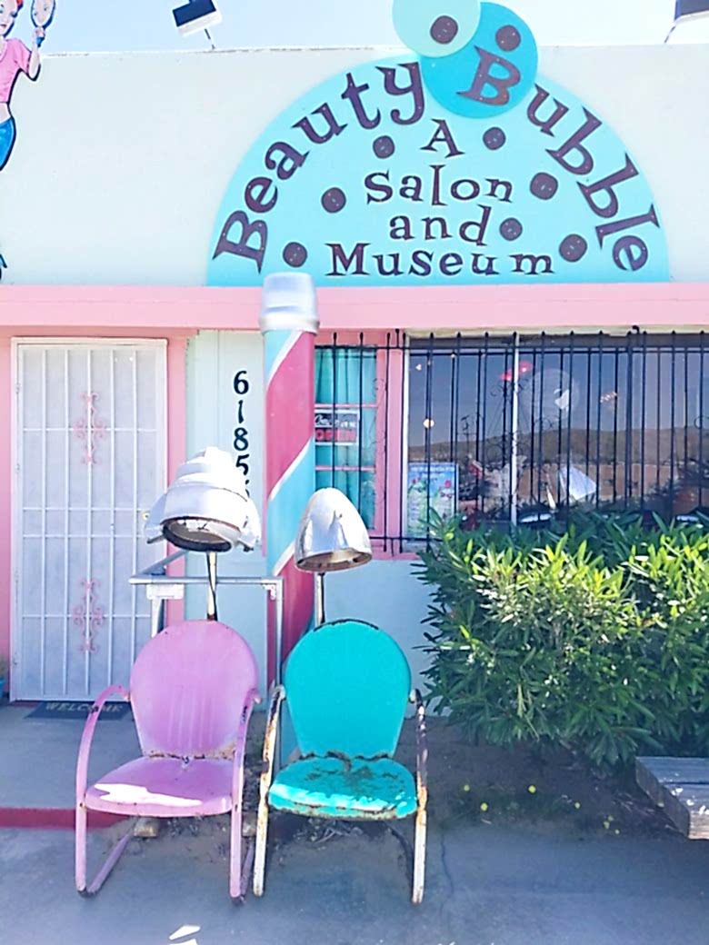 sidewalk in front of beauty bubble salon and museaum with two vintage blue and pink salon chairs