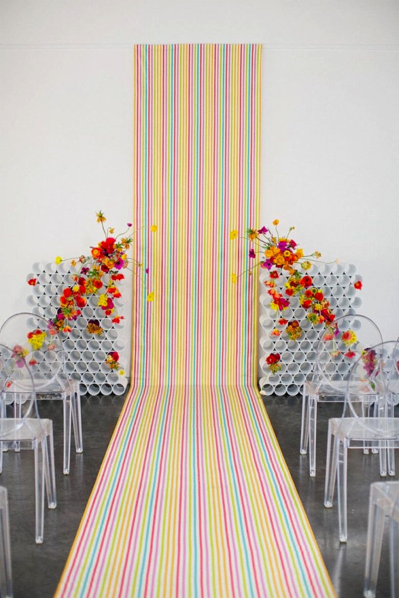 neon verticle stripe background and aisle runner with modern sculpural flowers and clear chairs