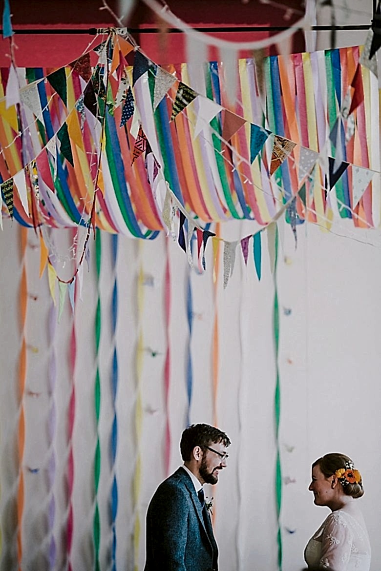 couple stands beneath draped ribbon and pendant flag banners