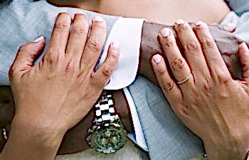 A man embraces a woman from behind, their arms interlocking.
