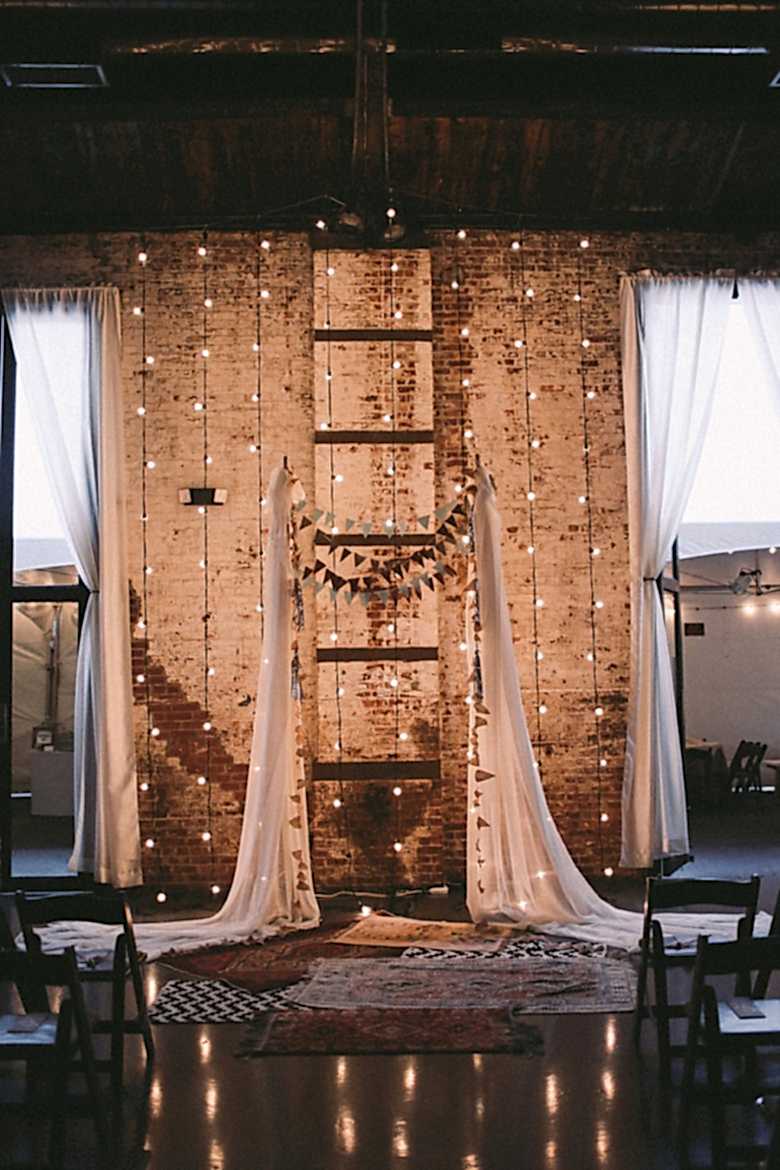tring lights hang vertically in front of a textured brick wall with fabric draping and bunting