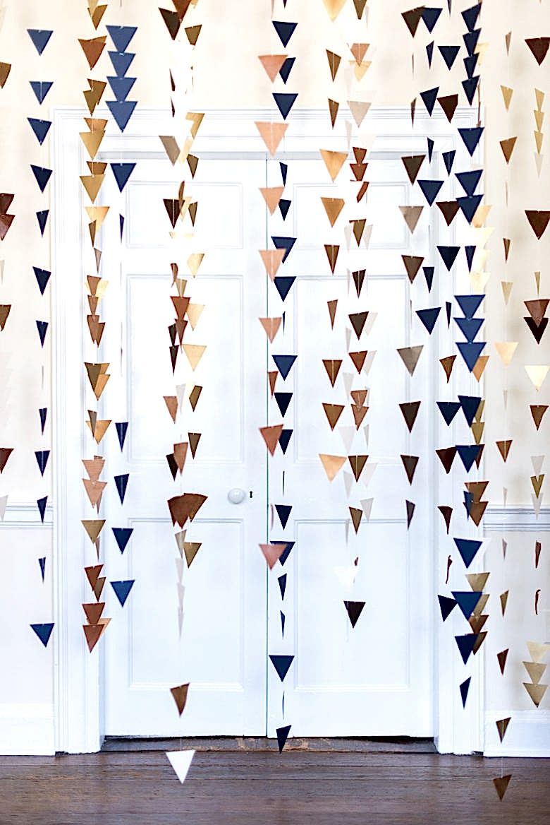 multi-colored strings of triangles hang from ceiling in front of white door