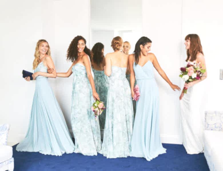 Group of four bridesmaids wearing blue floral gowns and a bride.