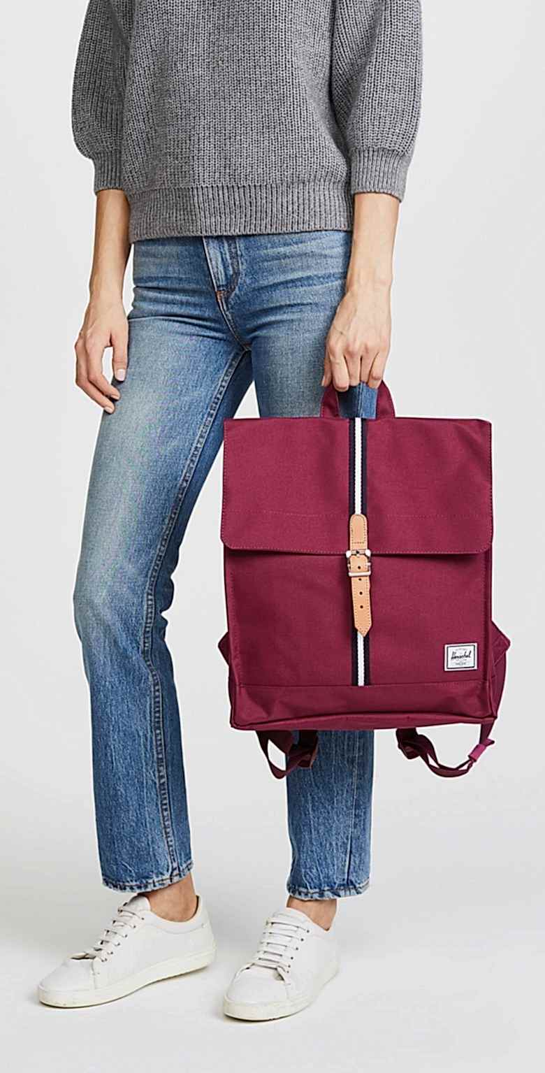 woman holding burgundy backpack