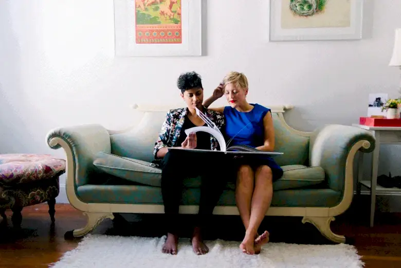 A couple sitting on a couch flipping through an album.