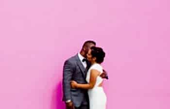wedding couple standing in front of a pink wall