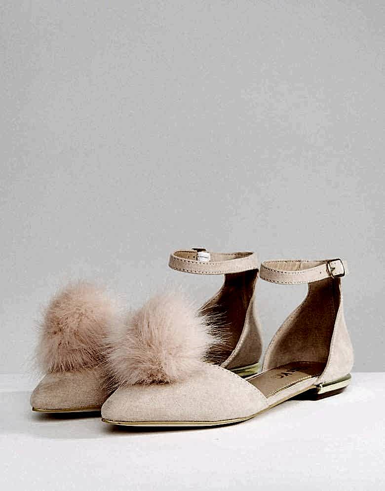 a pair of flats with a peach pom