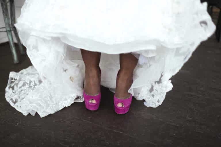 close up on a black bride lifting up her wedding dress slightly to show her hot pink platform wedding shoes
