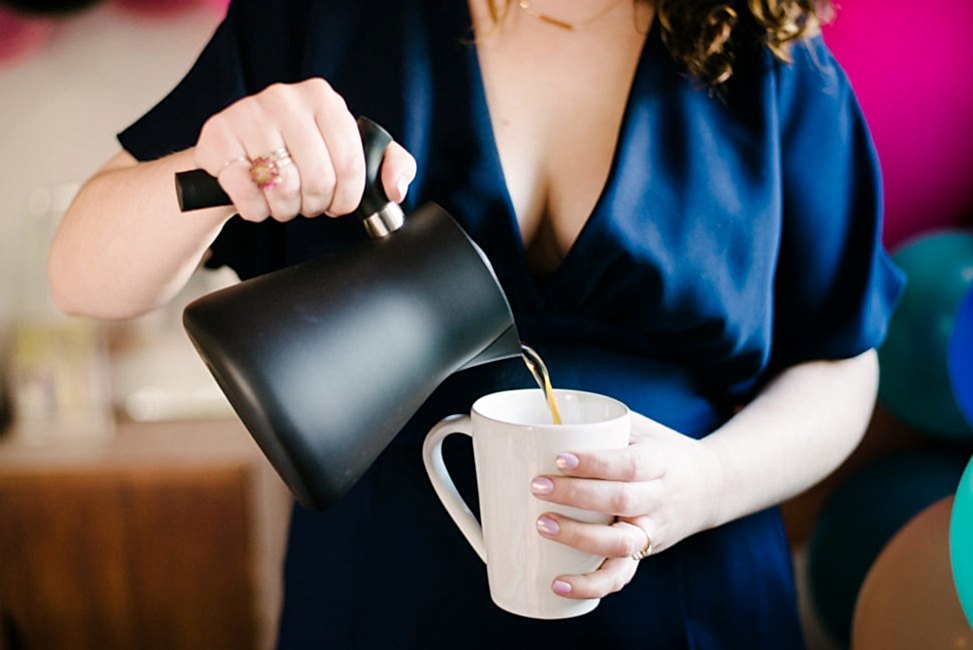 woman pouring tea from a black matte tea kettle into marin coffee mug from crate and barrel