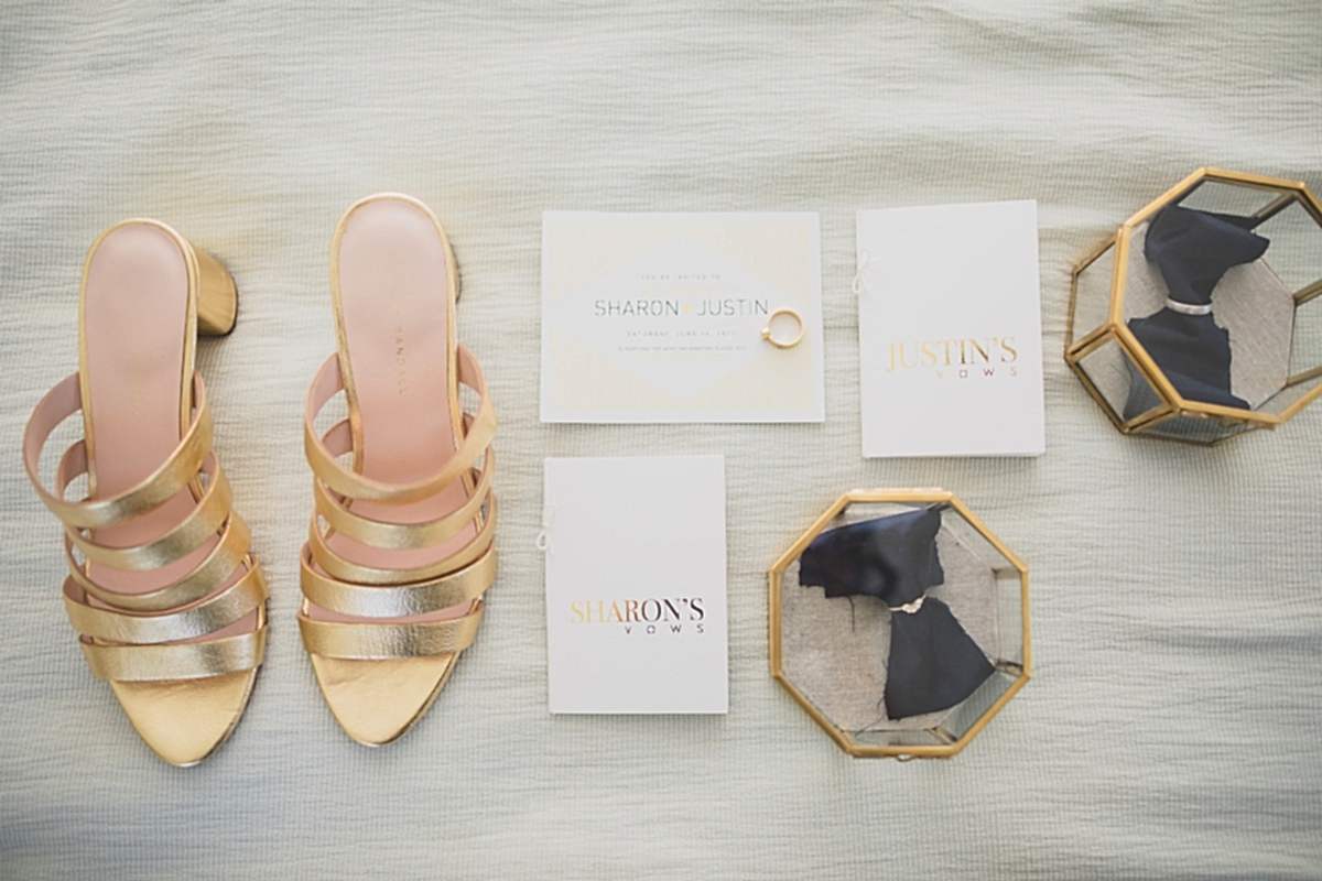 a layflat of day-of wedding essentials including gold high heeled shoes, printed foiled vows, and wedding rings