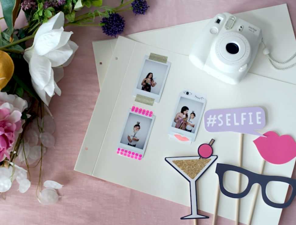 photo album pages with instant photos taped to them sitting beside a camera and photo props