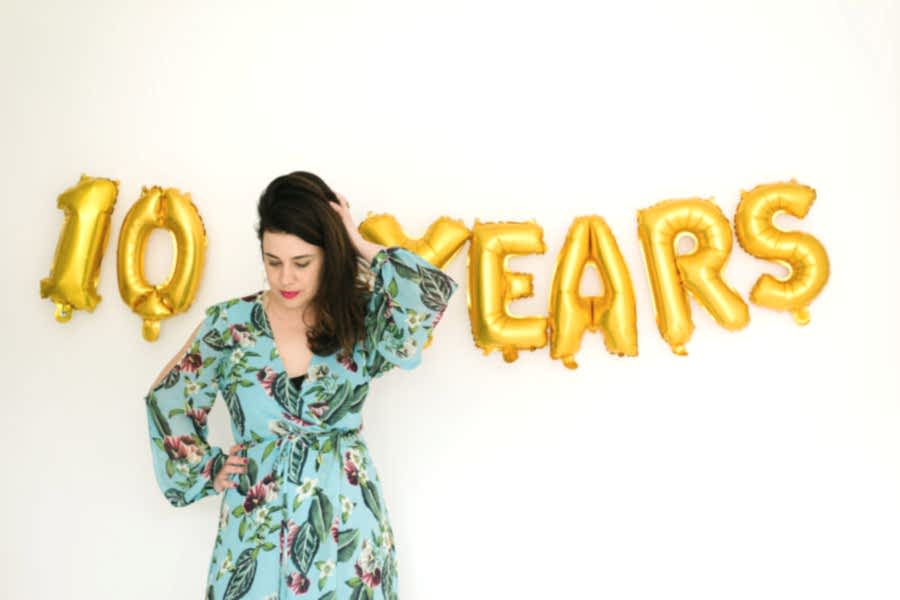 Meg Keene standing in front of a "10 Years" balloon banner