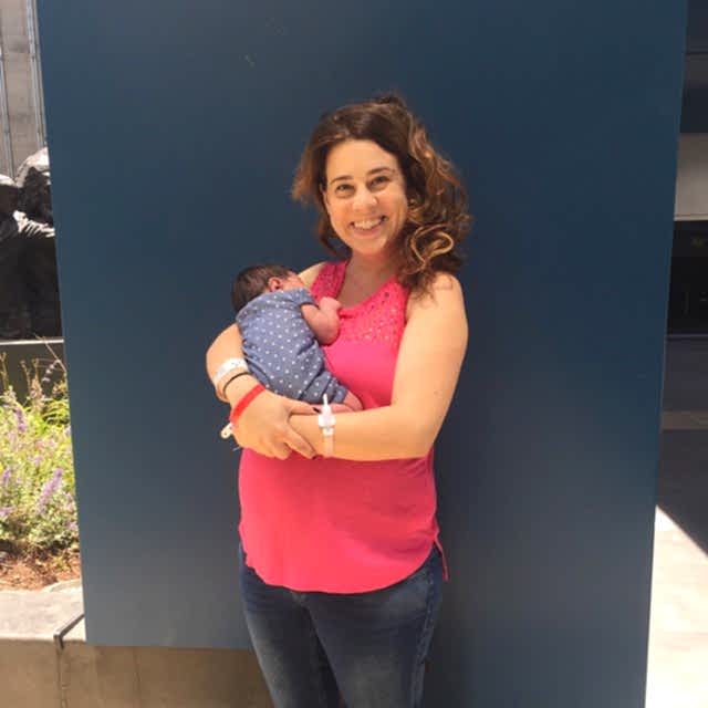 woman smiling, holding a tiny newborn baby