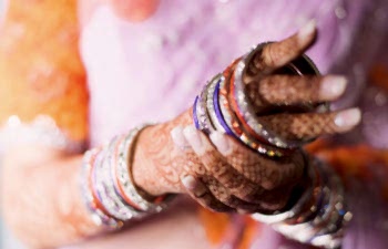 female hands with mehndi putting on sparkly bangle bracelets