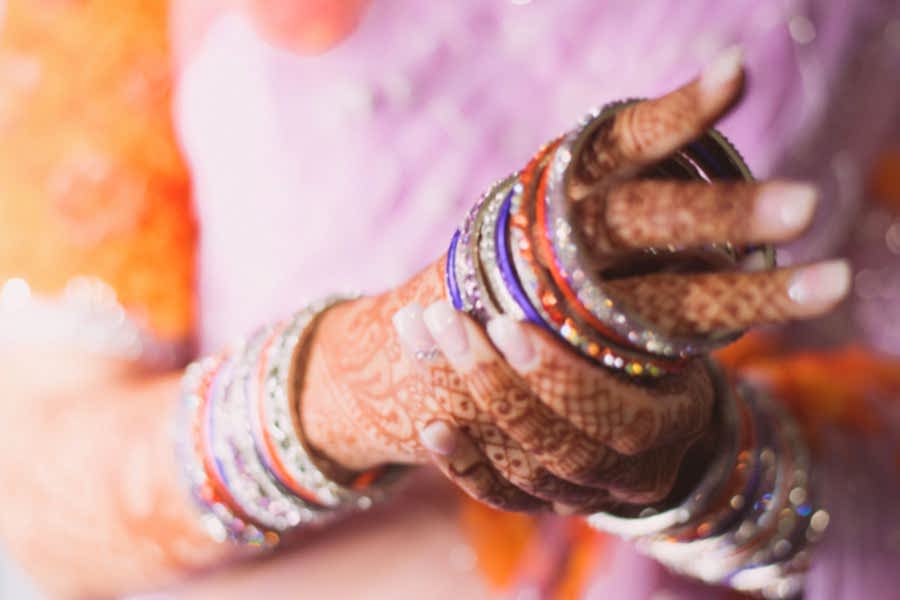female hands with mehndi putting on sparkly bangle bracelets