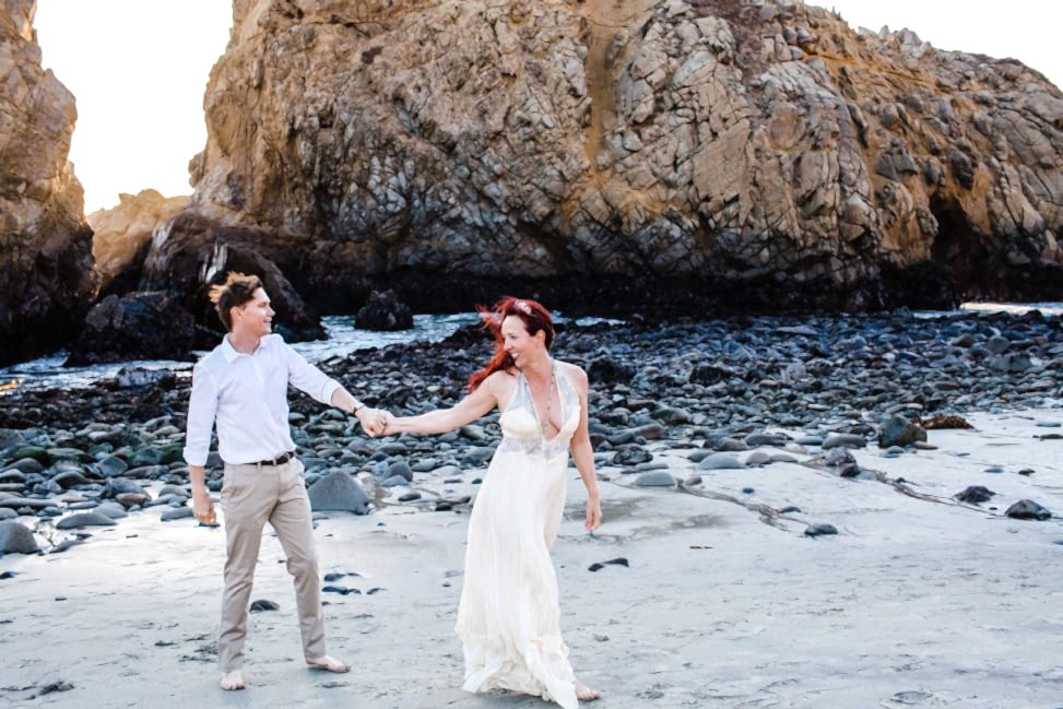 a woman pulls a man to walk with her on a beach
