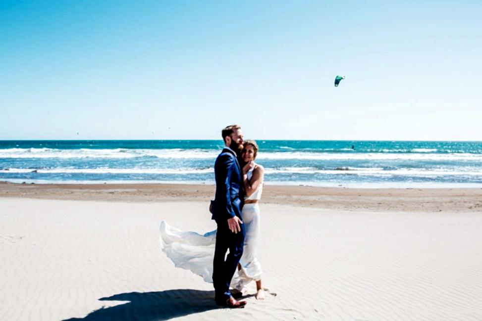 waves at a sunny beach with a happy couple standing around