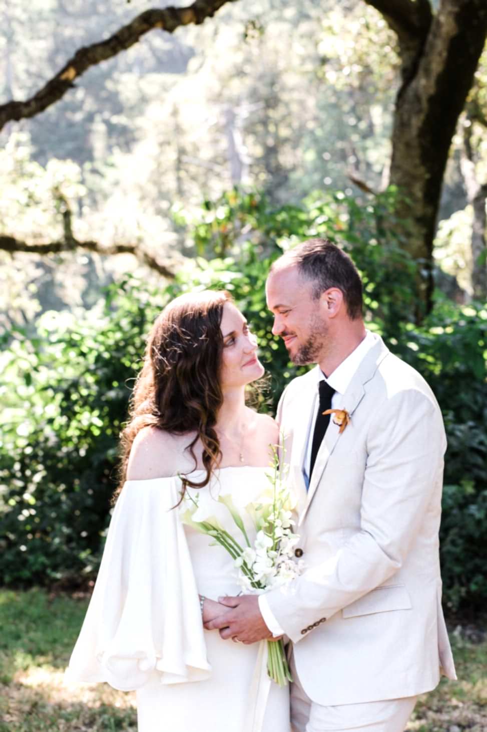 two people in the woods, holding hands, smiling at eachother