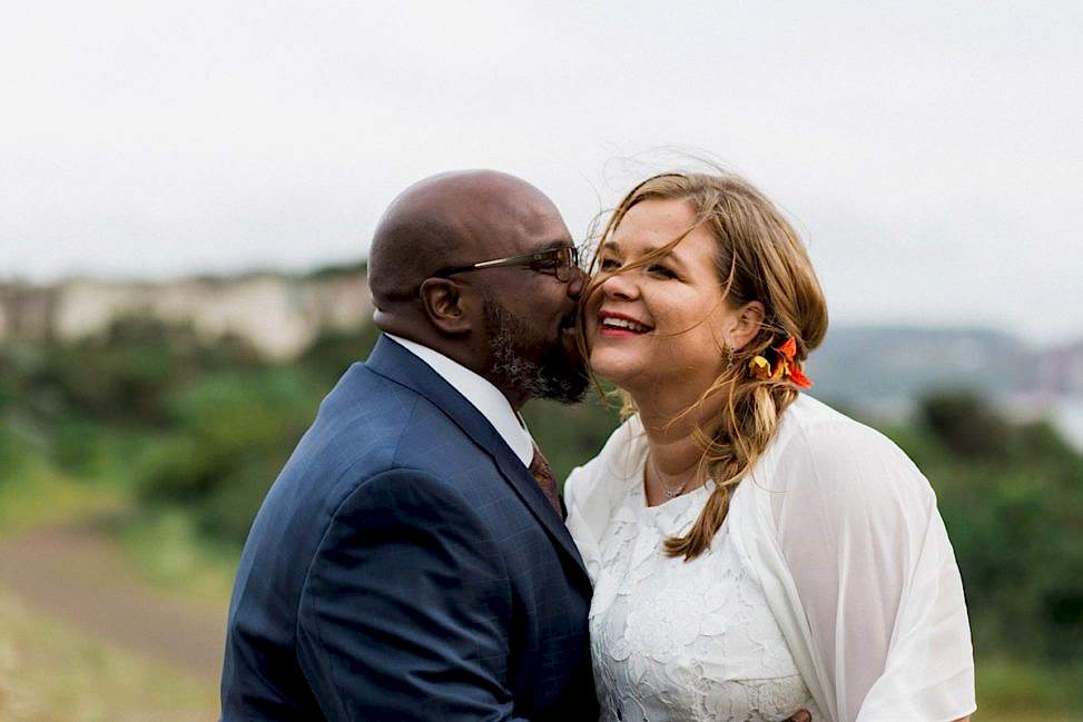 a man touching his face to a woman's face; both smile in the wind