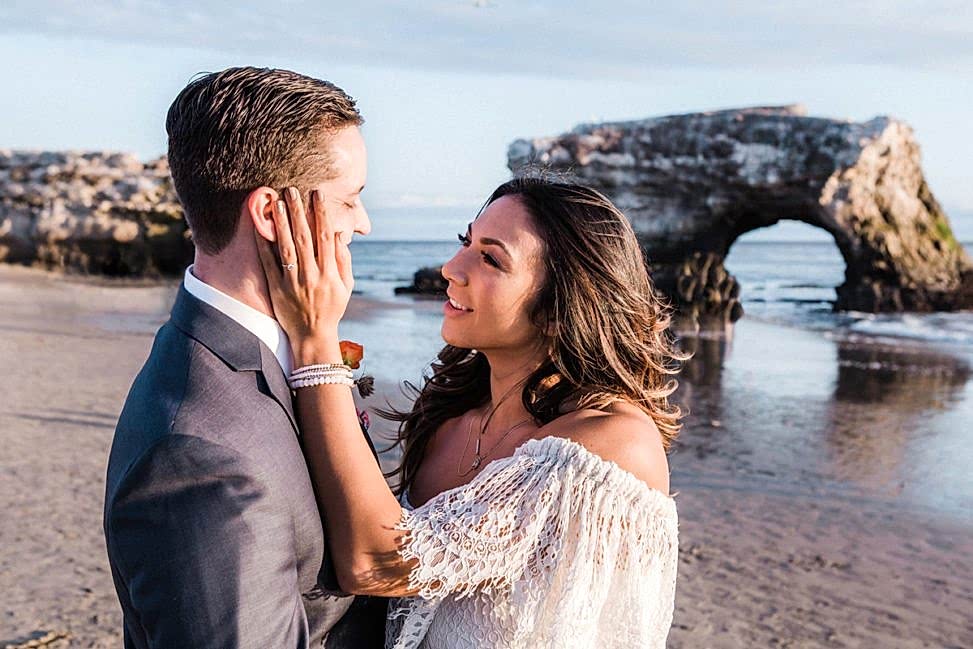 a woman touches a man's face at the beach