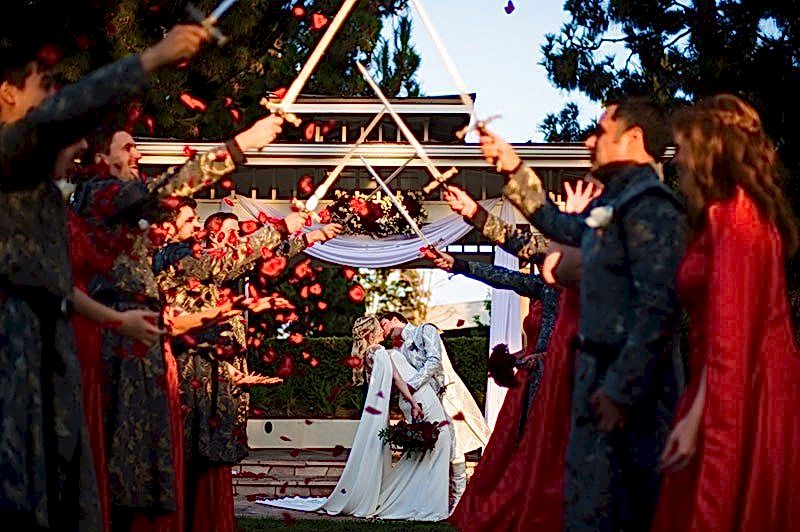 bride and groom kiss in front of swords