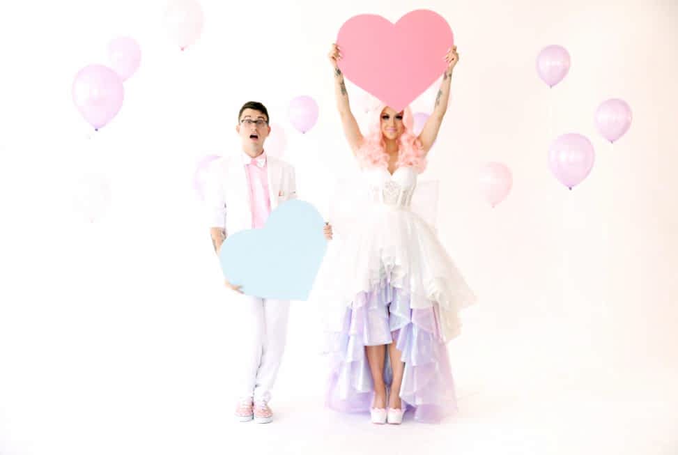 couple wearing colorful formal wear and holding heart props