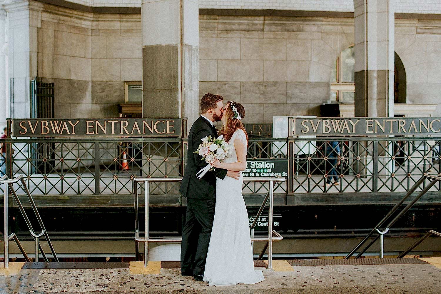 bride and groom kissing at a subway entrance