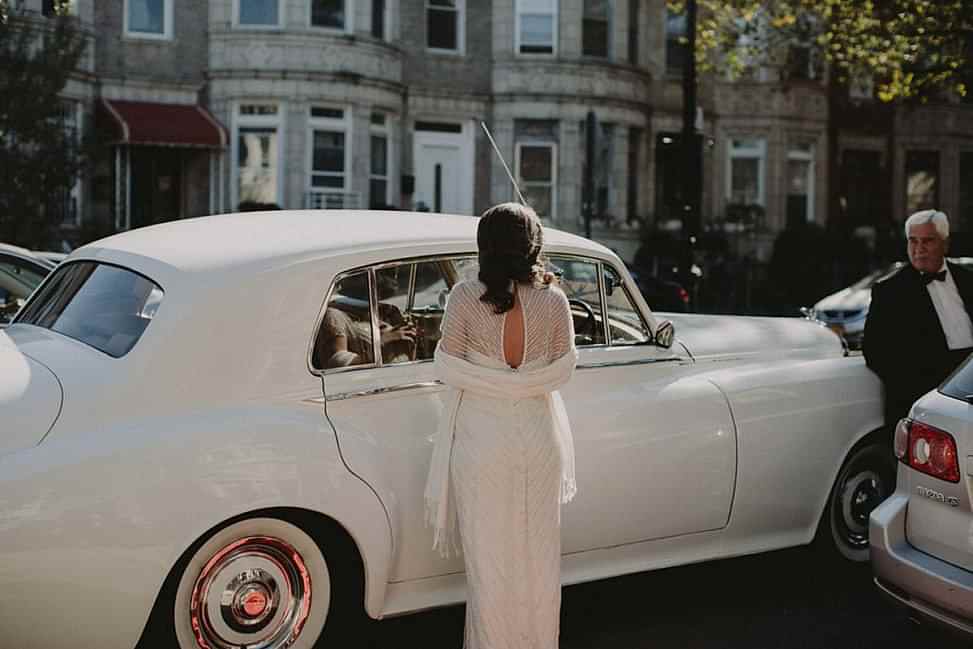 bride wearing vintage dress in front of a classic car