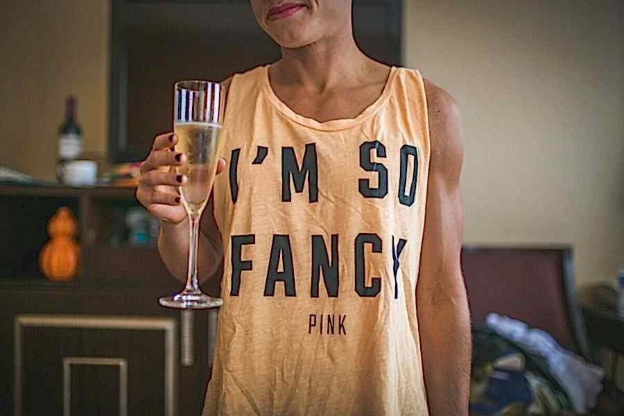 Woman holds glass of champagne while wearing a shirt that reads I'm So Fancy