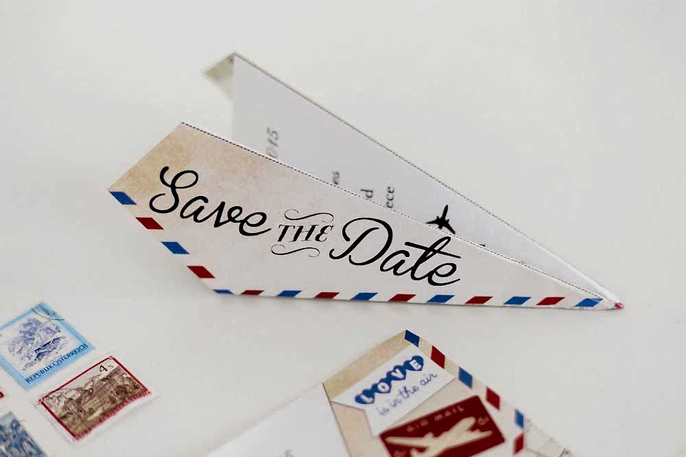air mail style envelope for a save the date folded into a paper airplane