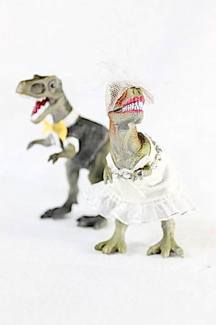 t-rex dinosaurs dressed as a bride and groom wedding cake toppers