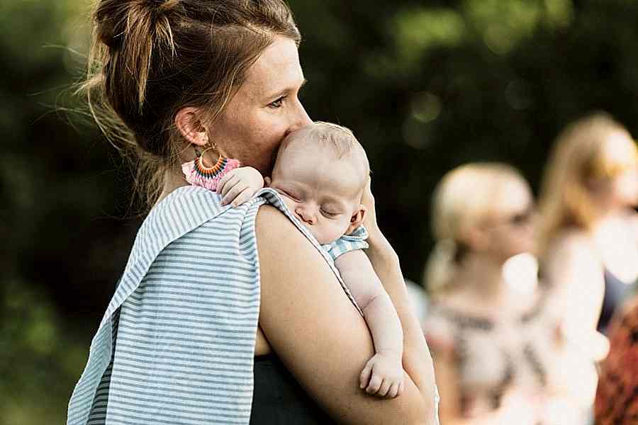 Woman holding sleeping baby at a wedding