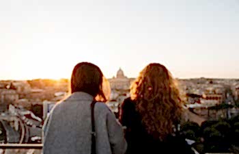two woman looking at view with golden sun shining down