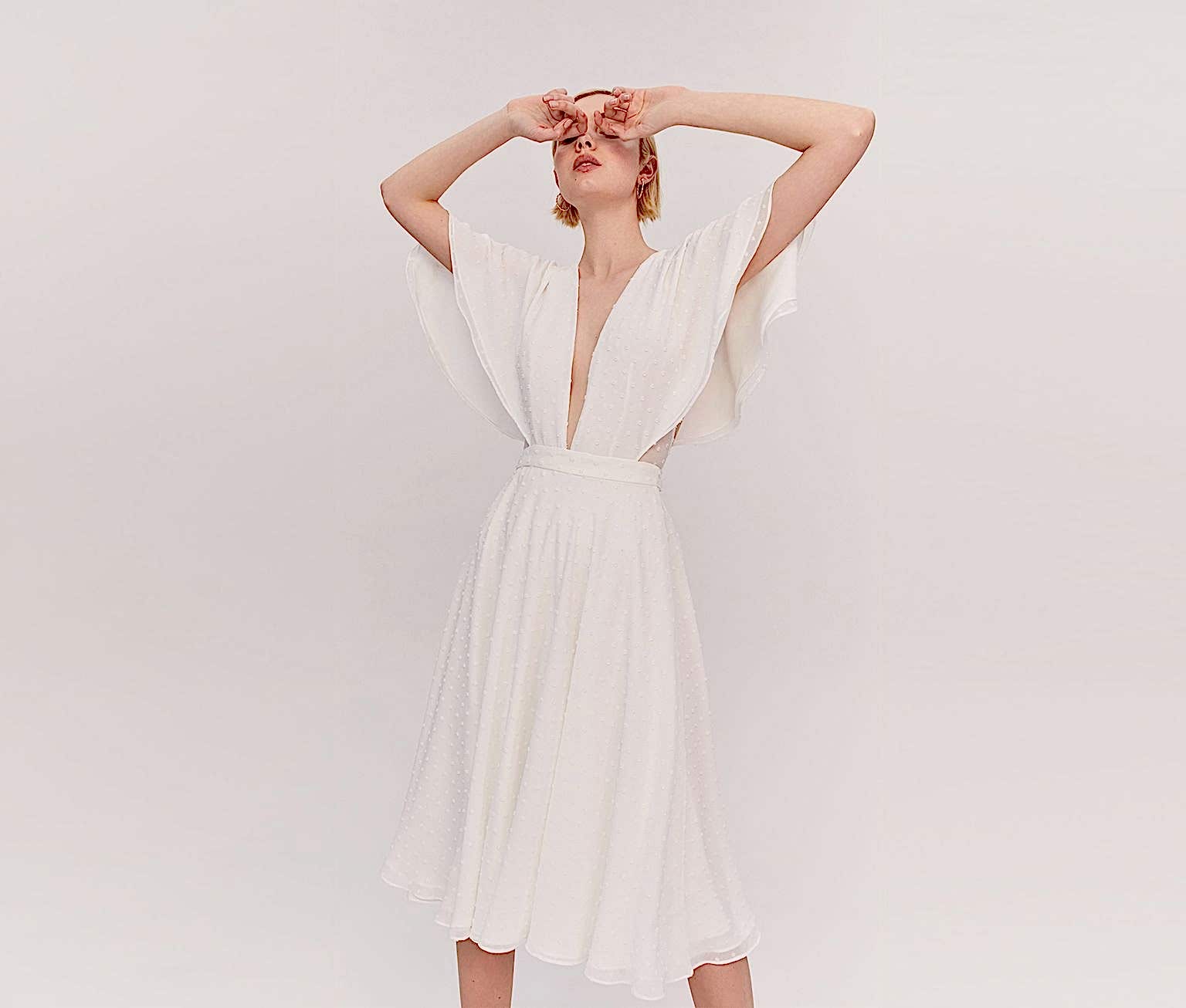 woman wearing a dress with a plunging neckline, floaty short sleeves, and a knee-length skirt