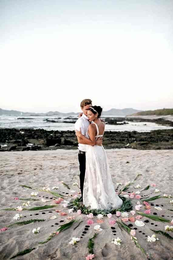 Bride and a groom in a flower mandala at a beach wedding