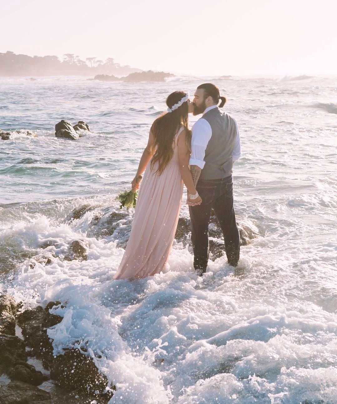A man and woman kiss while ocean water surrounds them