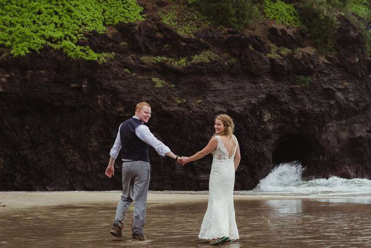 Two people hold hands, at the beach.